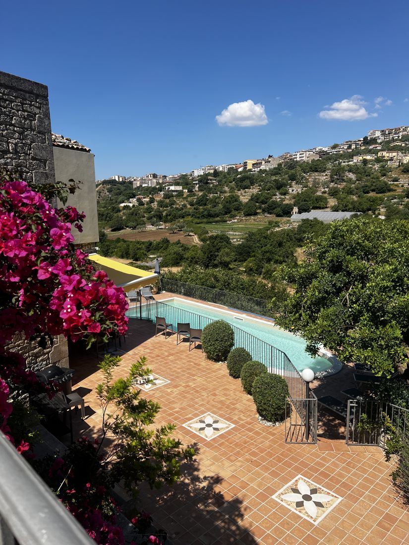 The pool terrace with bougainvillea, looking out over the Sicilian hillside town