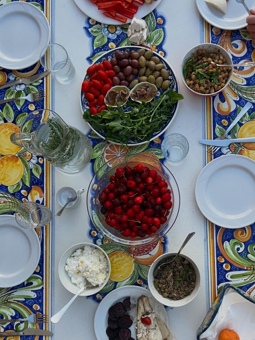 The table laid with olives, tomatoes, greens, ricotta and cherries on Sicilian majolica